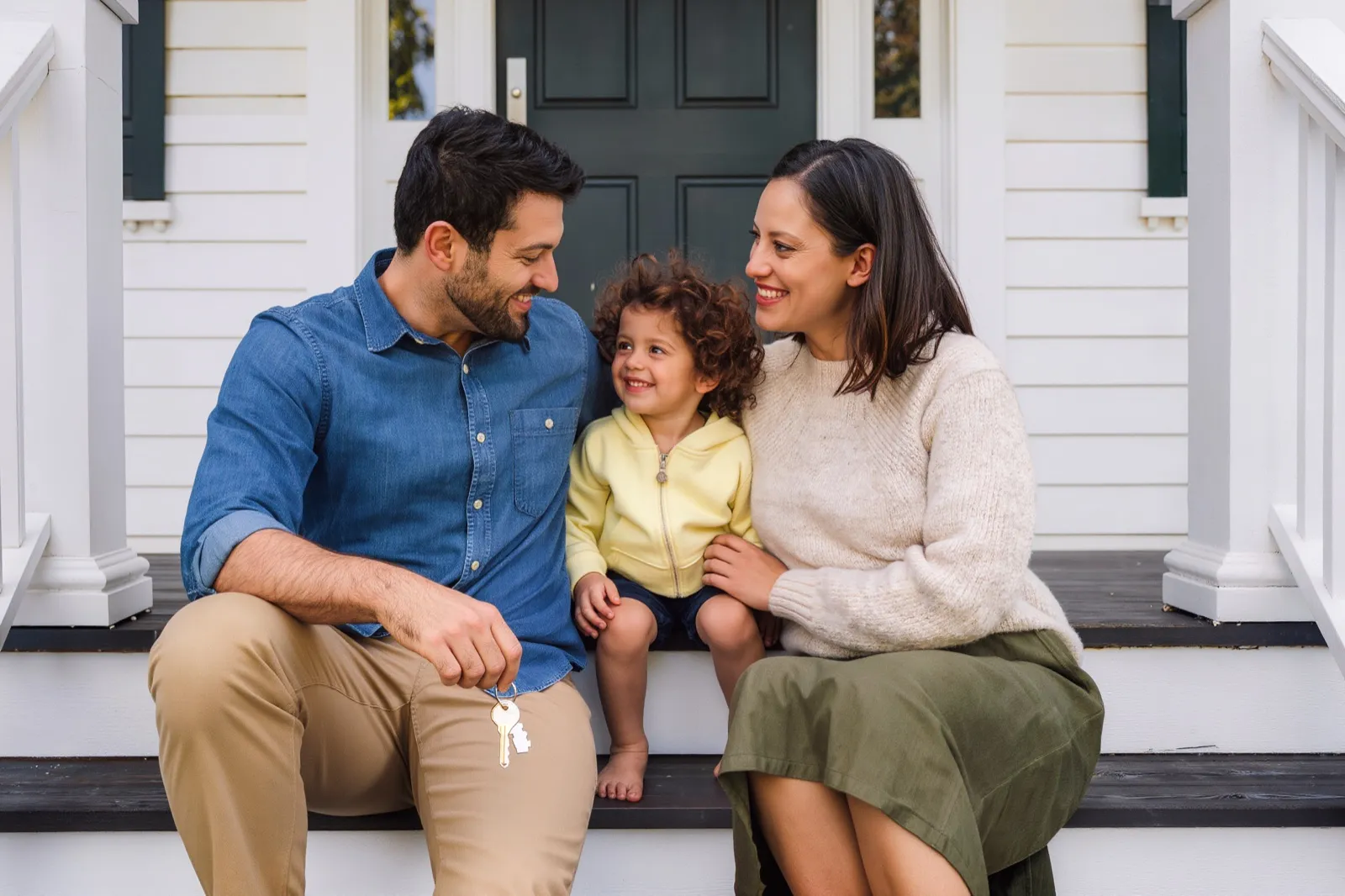 A family sitting together on the front steps of their home